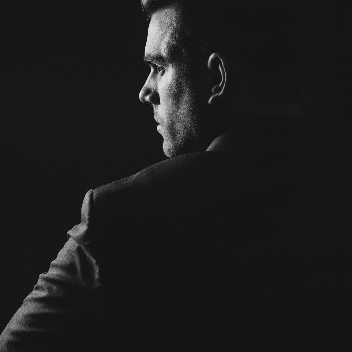 Direction marketing et communication externalisée | VISUELROUGE Un homme en costume et cravate, regardant au loin, avec une expression pensive.