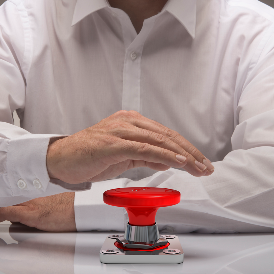 Main en chemise blanche au-dessus d'un bouton rouge sur un support métallique.