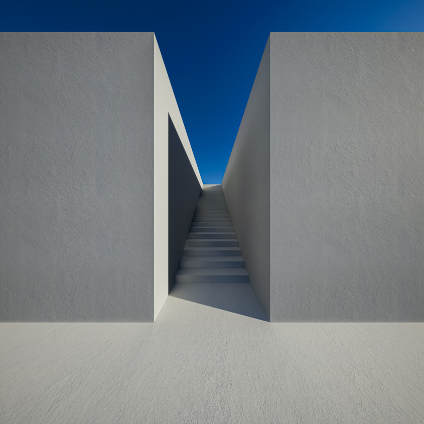 Chemin étroit entre deux murs gris, éclairé par un ciel bleu sans nuages.